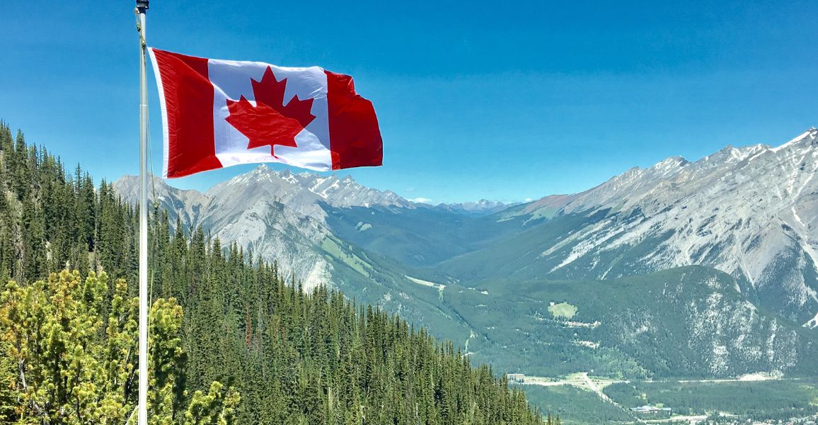 Candian flag blowing in the wind on a mountain range