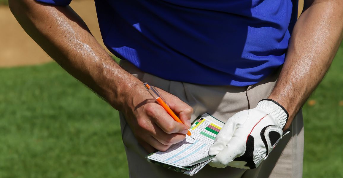 golfer writing down his score of a scorecard after checking the stroke index
