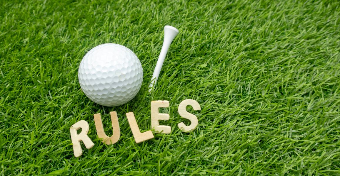 Golf ball laying on the grass above the word Rules