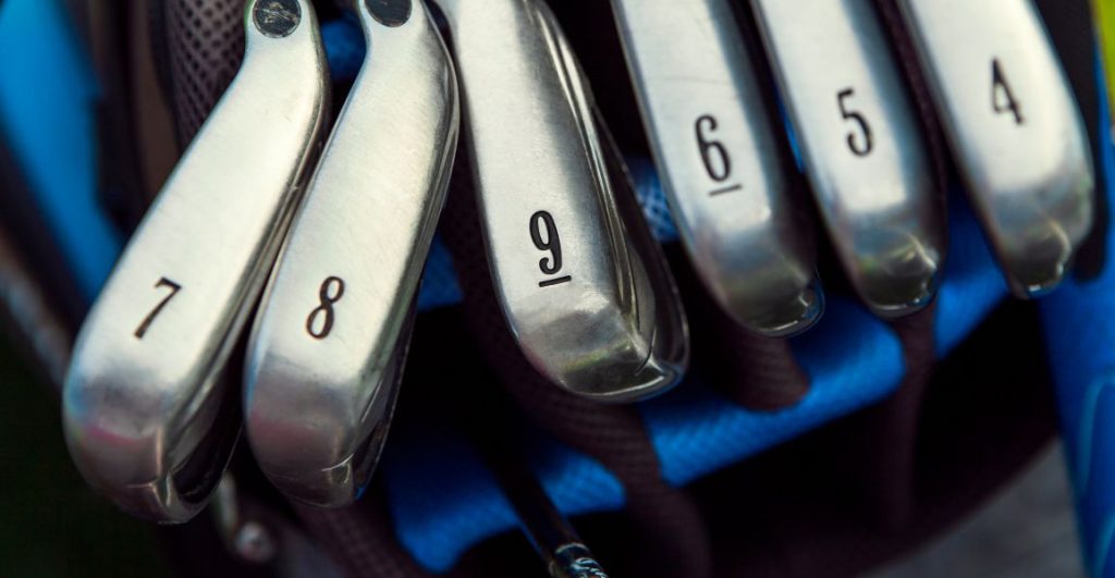 Golf irons with numbers on their club heads in a blue golf bag